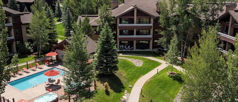 A resort with a swimming pool, lounge chairs, and a well-maintained lawn.