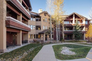 Un immeuble à plusieurs étages doté d’une cour intérieure, d’un espace extérieur aménagé pour s’asseoir et d’un jardin bien entretenu.