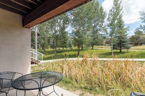 An outdoor patio area with a table and chairs, overlooking a grassy landscape with trees and a clear sky. - CL3106 | Beautifully Decorated | A/C | Short Walk to Slope | Hot Tubs (Steamboat Springs)