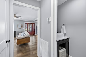 A modern interior with a wooden floor, a white sofa, a fireplace, and a bathroom with a towel rack.