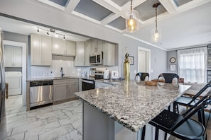 A modern kitchen with granite countertops, stainless steel appliances, and pendant lighting.