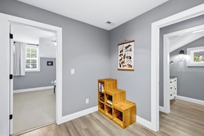 A hallway with a wooden bookshelf, a framed animal illustration, and a white dresser.
