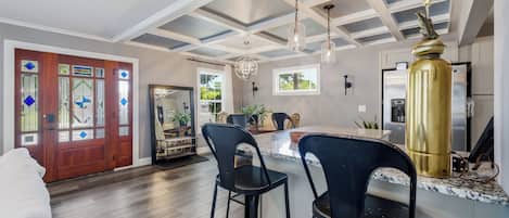 A modern kitchen with a central island, bar stools, a refrigerator, and a pendant light.