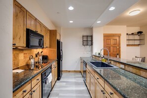 A modern kitchen with wooden cabinets, a granite countertop, a stainless steel kettle, and a built-in oven. - CL3107 | Beautifully Appointed Mtn Condo | 10 Hot Tubs | Pools | Winter Shuttle (Steamboat Springs)