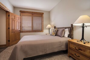 A bedroom with a bed, two bedside tables with lamps, a wooden headboard, a window with blinds, and a wooden wardrobe. - CL3107 | Beautifully Appointed Mtn Condo | 10 Hot Tubs | Pools | Winter Shuttle (Steamboat Springs)