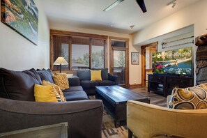 A living room with a sofa, coffee table, and a television on a stand. - CL3107 | Beautifully Appointed Mtn Condo | 10 Hot Tubs | Pools | Winter Shuttle (Steamboat Springs)