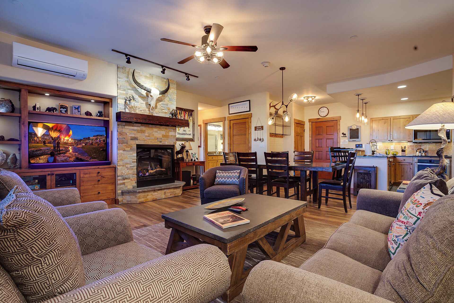 A cozy living room with a fireplace, a dining area, and a kitchen.