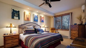 Ein Schlafzimmer mit einem großen Bett, zwei Nachttischen, einem Deckenventilator und Kunstwerken an den Wänden.