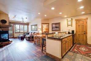 A spacious living area with a fireplace, a dining table, and a kitchen with wooden cabinets and a tiled backsplash. - CL3202 | Cozy Mountain Home | Easy access to Mountain | A/C (Steamboat Springs)