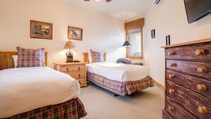 A bedroom with two beds, a wooden dresser, a ceiling fan, and framed pictures on the wall. - CL3202 | Cozy Mountain Home | Easy access to Mountain | A/C (Steamboat Springs)