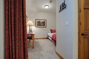 A bedroom with a bed, a nightstand, a lamp, a framed picture on the wall, and a door. - CL3205 | Great Family Condo | A/C | 10 Hot Tubs | Close to Slopes (Steamboat Springs)