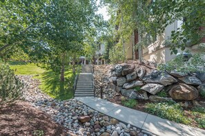 A pathway leading to a building with a stone wall and a metal railing. - CL3205 | Great Family Condo | A/C | 10 Hot Tubs | Close to Slopes (Steamboat Springs)