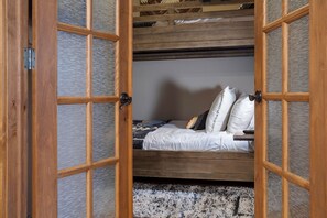 A bunk bed with a wooden frame and a mattress, pillows, and a remote control on the bed. - CL3206 | Perfect Condo for a Weekend Getaway | A/C | Close to Slopes (Steamboat Springs)