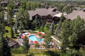 Aerial view of a vacation property featuring an outdoor pool area with hot tub, surrounded by mature trees and neighboring lodges in a peaceful mountain community setting. - CL3206 | Perfect Condo for a Weekend Getaway | A/C | Close to Slopes (Steamboat Springs)