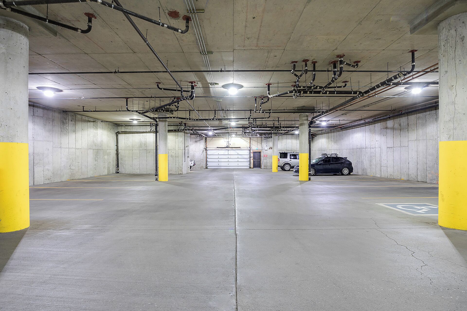 Eine mehrgeschossige Parkgarage mit Betonwänden, gelben Säulen und einem geparkten Auto in einer Box.