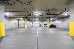 Een meerlaagse parkeergarage met betonnen muren, gele zuilen en een auto in een van de parkeerplaatsen.
