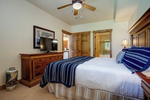 Ein Schlafzimmer mit Bett, Kommode, Fernseher und Deckenventilator.