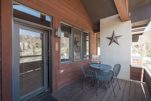 Eine Holzterrasse mit Tisch und Stühlen, eine Stern-Dekoration an der Wand und ein Fenster mit Jalousien.