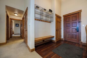 A hallway with wooden flooring, a bench, a door with a keyhole, and a wall-mounted rack with animal silhouettes. - CL3308 | A/C Units | Vaulted Ceilings | Great View | Hot Tubs | Close to Skiing (Steamboat Springs)