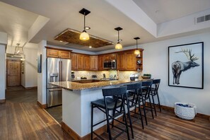 Gather at your spacious granite-topped island with seating for six. Warm wood cabinetry and stainless appliances make this fully-equipped kitchen ready for memorable meals together. - EL5105 | Private Patio with Hot Tub | Air Chilling | Close to Skiing | 4 Pools (Steamboat Springs)
