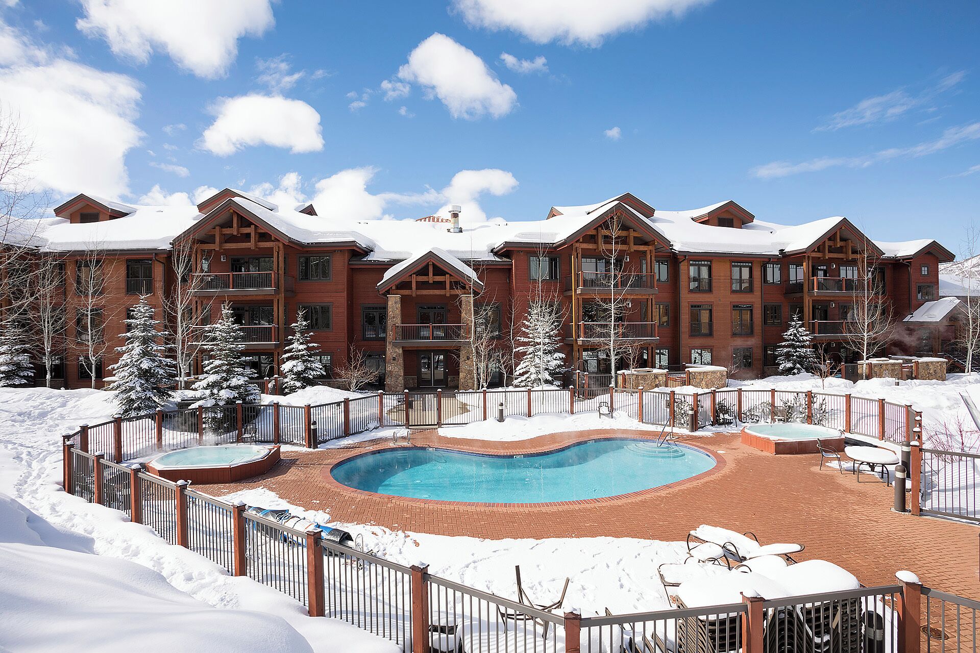 A resort with a pool, snow-covered landscape, and multiple buildings with balconies.