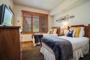 A bedroom with two beds, a wooden headboard, a bedside table with a lamp, and a television on a stand. - EL5105 | Private Patio with Hot Tub | Air Chilling | Close to Skiing | 4 Pools (Steamboat Springs)