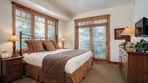 A bedroom with a large bed, two bedside tables, a dresser, a television, and large windows with blinds. - EL5106 | Enough room for Everyone | Air Chilling | Short Walk to Mtn (Steamboat Springs)