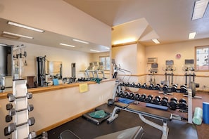Ein Fitnessstudio mit unterschiedlichen Trainingsgeräten, darunter Laufbänder, Kraftgeräte und Kurzhanteln.