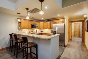 Eine moderne Küche mit Holzschränken, einem Edelstahlkühlschrank und einer Arbeitsplatte aus Granit.