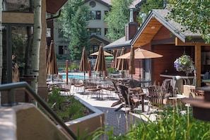 An outdoor patio area with tables and chairs, umbrellas, and a pool. - EL5110 | Private Hot Tub | 4 Pools | Air Chilling | Close to Skiing (Steamboat Springs)