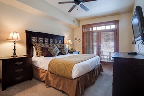 A bedroom with a bed, two bedside tables, a ceiling fan, a window with blinds, and a television on a stand. - EL5110 | Private Hot Tub | 4 Pools | Air Chilling | Close to Skiing (Steamboat Springs)