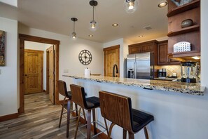 Gather around the sleek breakfast bar with cozy seating, perfect for morning coffee or casual meals. The granite countertops, modern lighting, and fully equipped kitchen make your stay feel effortlessly at home. - EL5111 | Private Courtyard with Hot Tub | Air Chilling | Close to Slope (Steamboat Springs)
