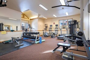 Un gimnasio con diverso equipo de ejercicio, incluyendo cintas de correr, mancuernas y máquinas de pesas.