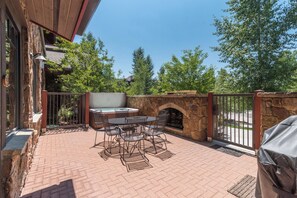 Un patio al aire libre con una chimenea de piedra, una mesa y sillas, y una parrilla.
