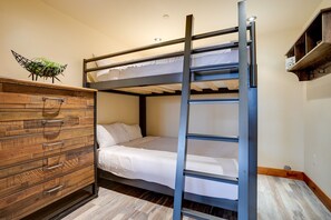 Una cama individual superpuesta con un aparador de madera y un soporte para bicicletas.