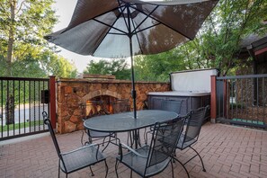 Eine Außenpatio mit Kamin aus Stein, Grill und Tisch mit Stühlen.