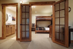 A bedroom with a bunk bed, wooden blinds, a small desk, and a mirror. - EL5112 | Private Patio with Hot Tub | Close to Mtn | Air Chilling | Pools (Steamboat Springs)