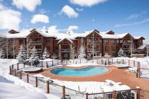 A resort with a pool, snow-covered landscape, and multiple buildings with balconies. - EL5114 | Close to Mtn Activities | Private Hot Tub | Air Chilling | 4 Pools (Steamboat Springs)