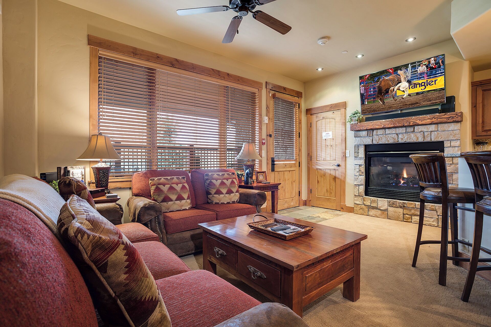 A living room with a fireplace, a television mounted above it, and a ceiling fan.