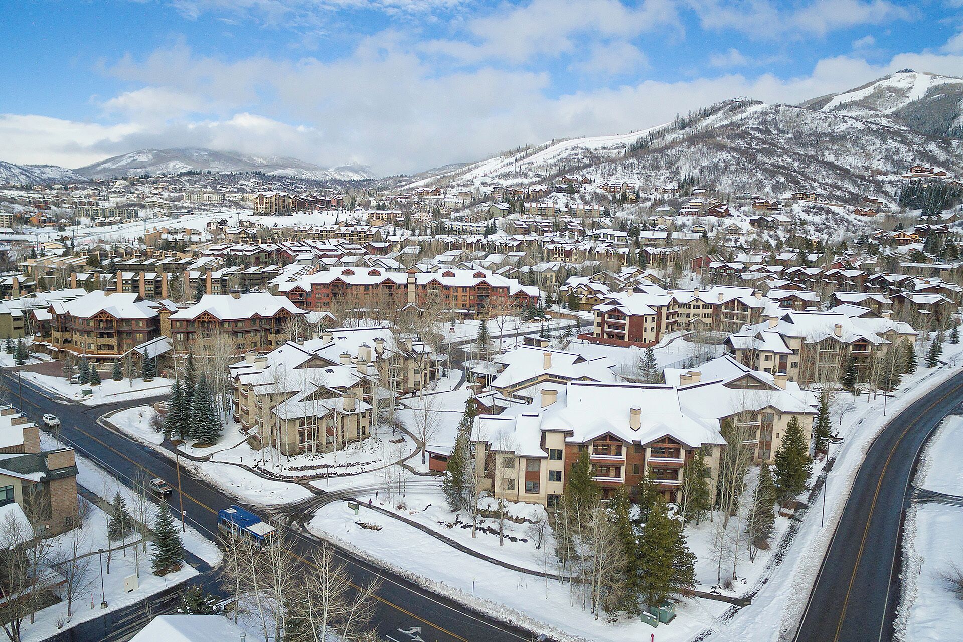 Une ville enneigée avec de nombreux bâtiments, des rues et une montagne en arrière-plan.