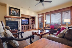 A living room with a fireplace, television, wooden furniture, and large windows with blinds. - EL5204 | Ultimate Mountain Getaway | Air Chilling | Close to Mtn | Pools (Steamboat Springs)