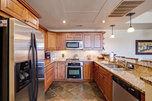 A modern kitchen with wooden cabinets, stainless steel appliances, a granite countertop, and a tiled backsplash. - EL5204 | Ultimate Mountain Getaway | Air Chilling | Close to Mtn | Pools (Steamboat Springs)