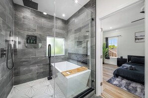 Een moderne badkamer met een douchecabine, een badkuip en een groot raam.