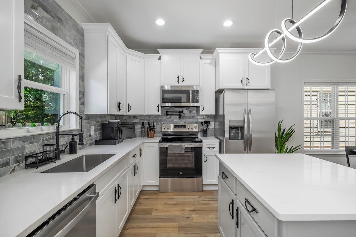 A modern kitchen with white cabinets, stainless steel appliances, and a large island.