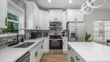 A modern kitchen with white cabinets, stainless steel appliances, and a large island.
