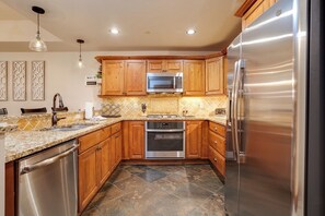 A modern kitchen with wooden cabinets, stainless steel appliances, and a tiled backsplash. - EL5209 | Gorgeous Second Floor Residence | Very Spacious | Air Chilling | Pool (Steamboat Springs)