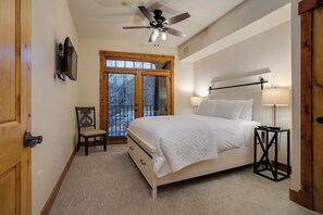 A bedroom with a bed, a chair, a desk, a lamp, a ceiling fan, and a window with blinds. - EL5209 | Gorgeous Second Floor Residence | Very Spacious | Air Chilling | Pool (Steamboat Springs)