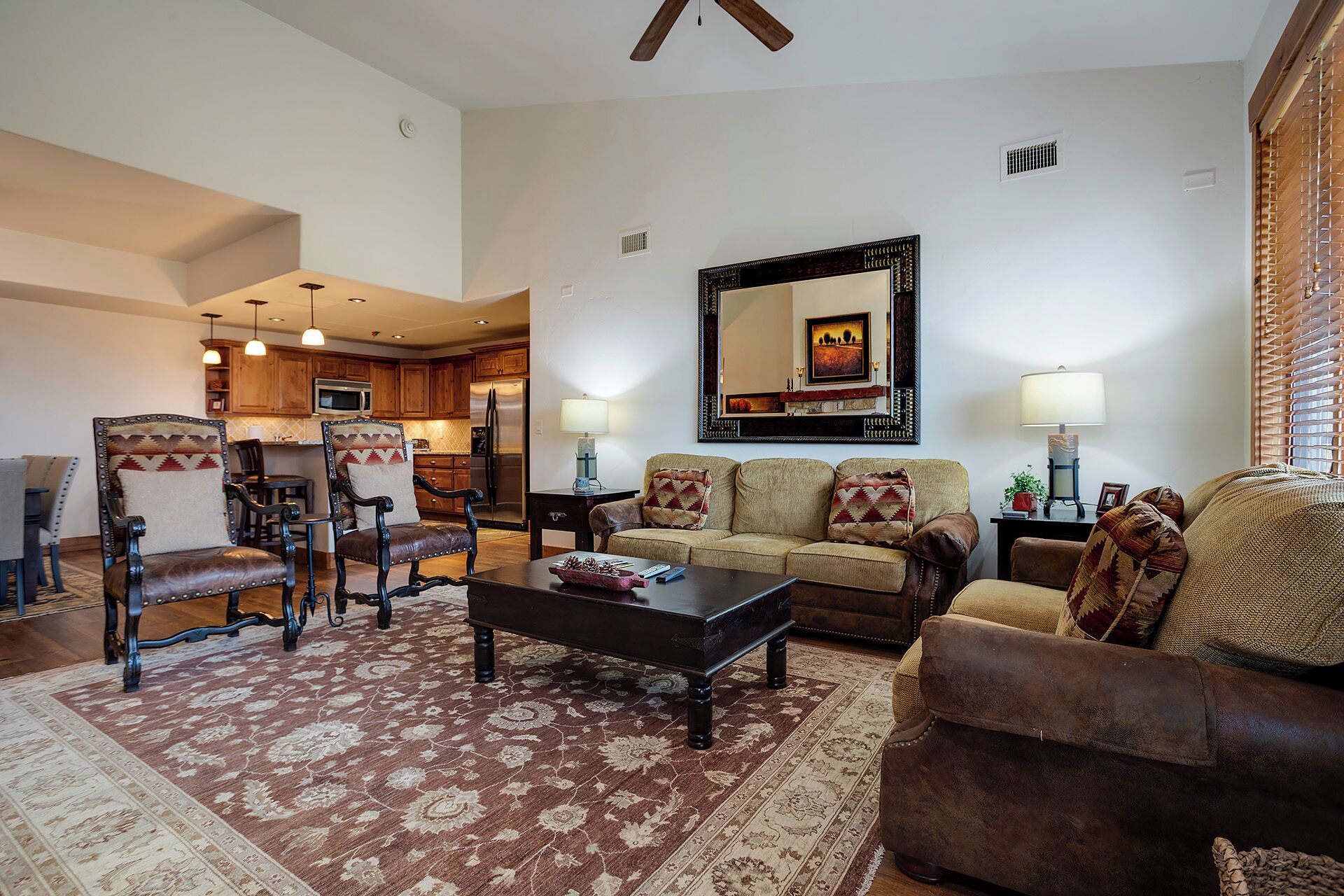 A living room with a sofa, armchairs, a coffee table, and a dining area with a chandelier.