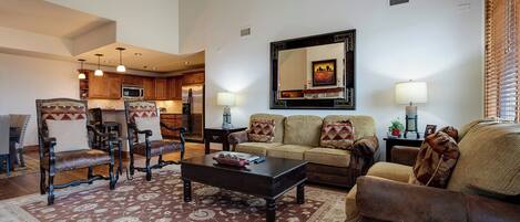 A living room with a sofa, armchairs, a coffee table, and a dining area with a chandelier.