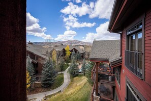A view of a building with a balcony, a pathway, and a mountain in the background. - EL5303 | Mtn Getaway | Resort Amenities | 2 King Suites | Air Chilling (Steamboat Springs)